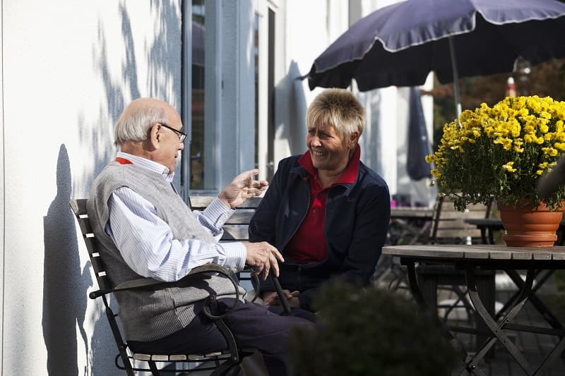 Ein Mann und eine Frau im Gespräch im Sonnenschein auf der Terrasse