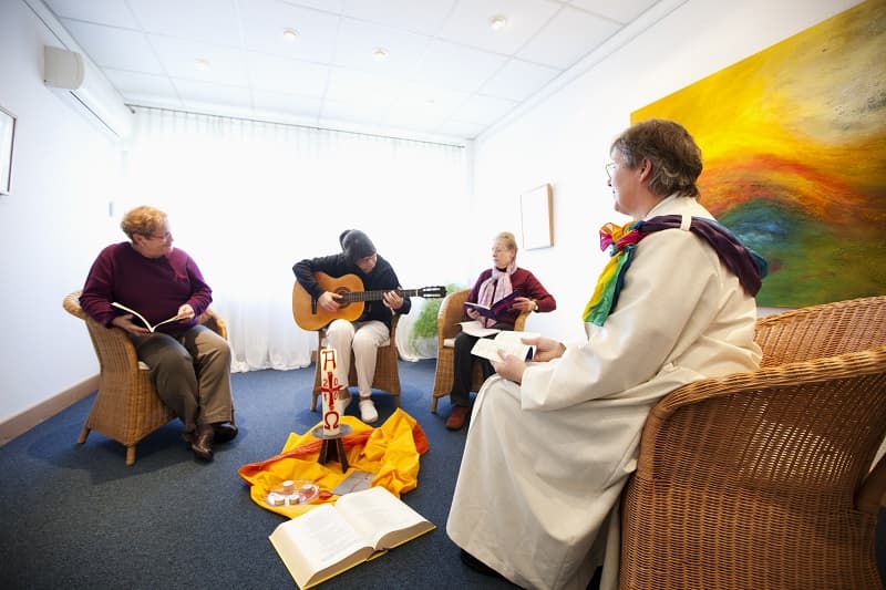 Vier Menschen sitzen in einem Kreis mit Gitarre.